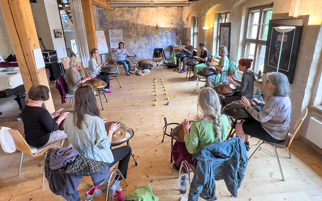 10 Handpanspielerinnen sitzen im Kreis bei einem Workshop in Wittenberg im Malsaal